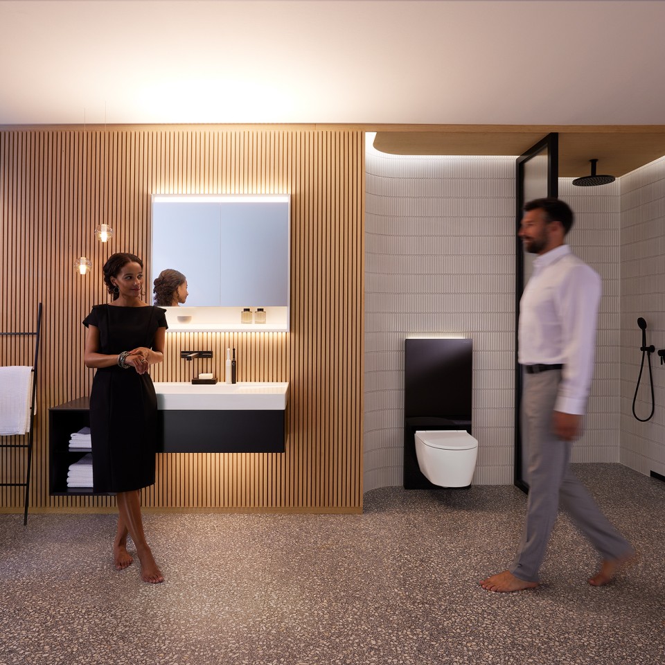 Hombre y mujer en un baño perfectamente iluminado con muebles de baño y sanitarios Geberit ONE (© Geberit)