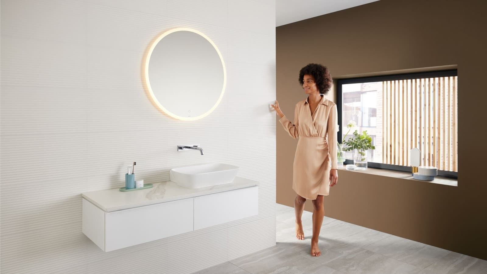 Mujer en un baño moderno con una paleta de colores marrones — la última tendencia en color para baños — y una combinación de lavabo Mix & Match. Mujer en un baño moderno con una paleta de colores marrones — la última tendencia en color para baños — y una combinación de lavabo Mix & Match.