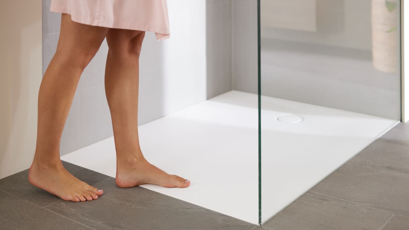 Mujer en un baño con plato de ducha Geberit integrado en el pavimento Mujer en un baño con plato de ducha Geberit integrado en el pavimento