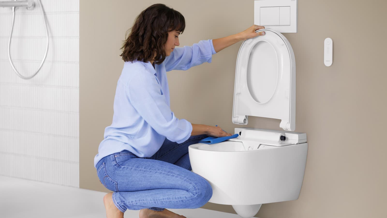 Mujer limpiando un inodoro bidé Geberit AquaClean Alba Mujer limpiando un inodoro bidé Geberit AquaClean Alba