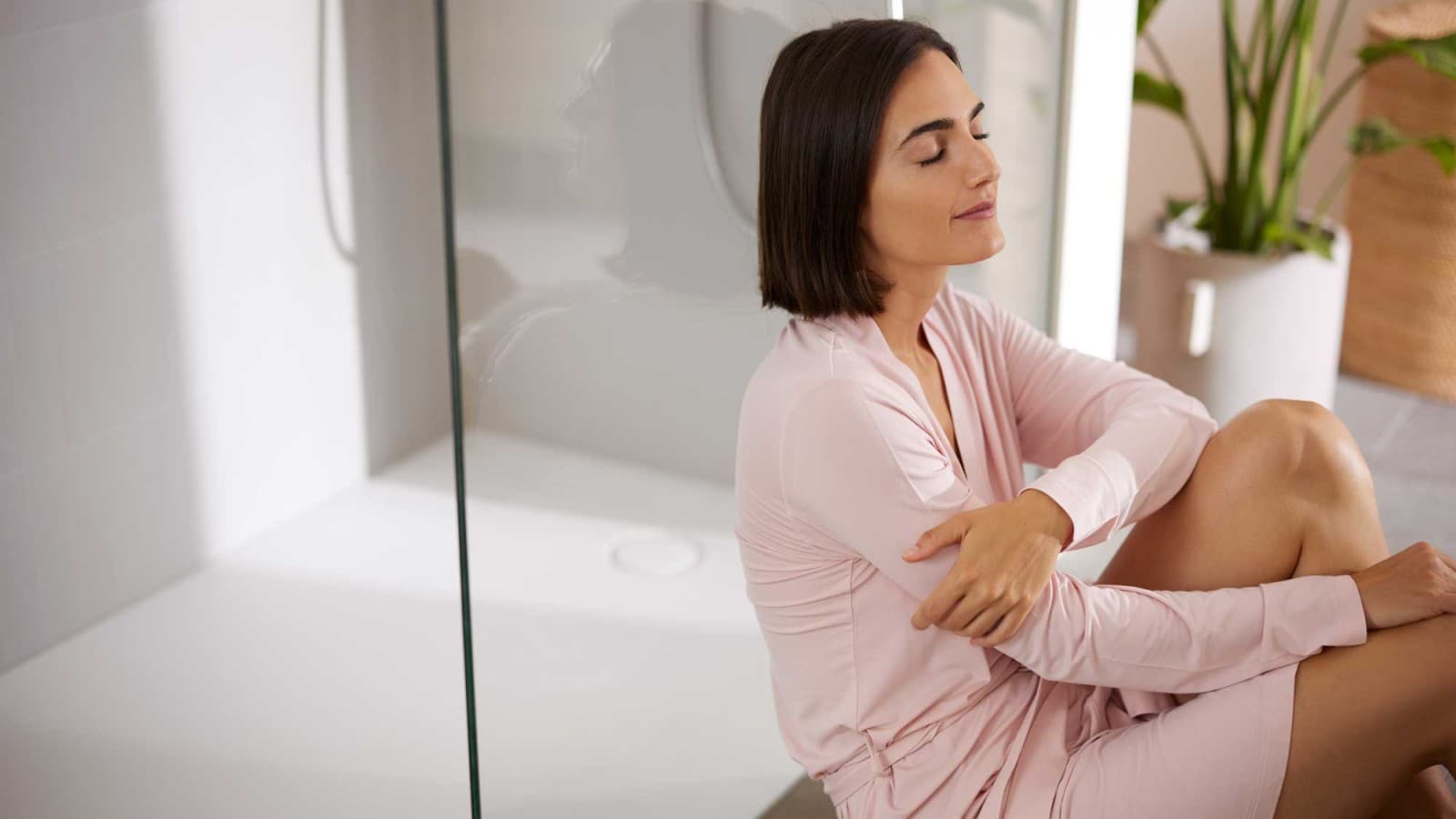 Mujer sentada en el baño frente a la ducha Mujer sentada en el baño frente a la ducha